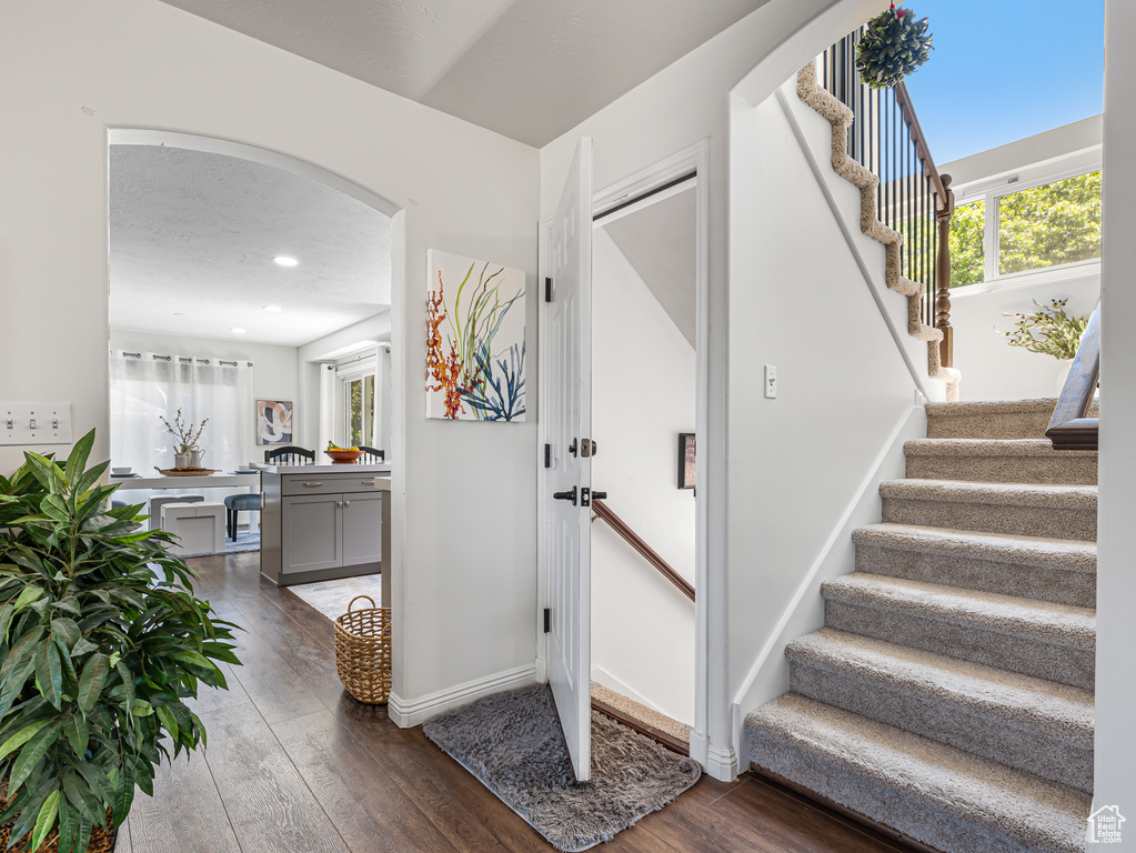 Foyer with hardwood / wood-style floors, stairs, arched walkways, recessed lighting, and baseboards