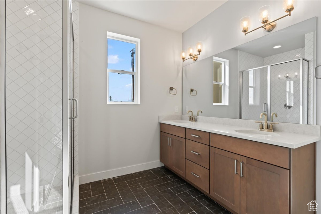 Full bath with baseboards, double vanity, plenty of natural light, and brick patterned flooring