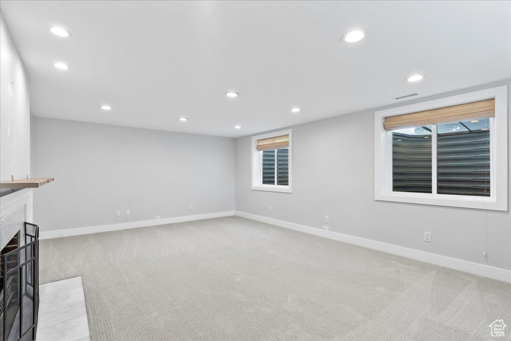 Unfurnished living room with light carpet, recessed lighting, baseboards, and a fireplace with flush hearth