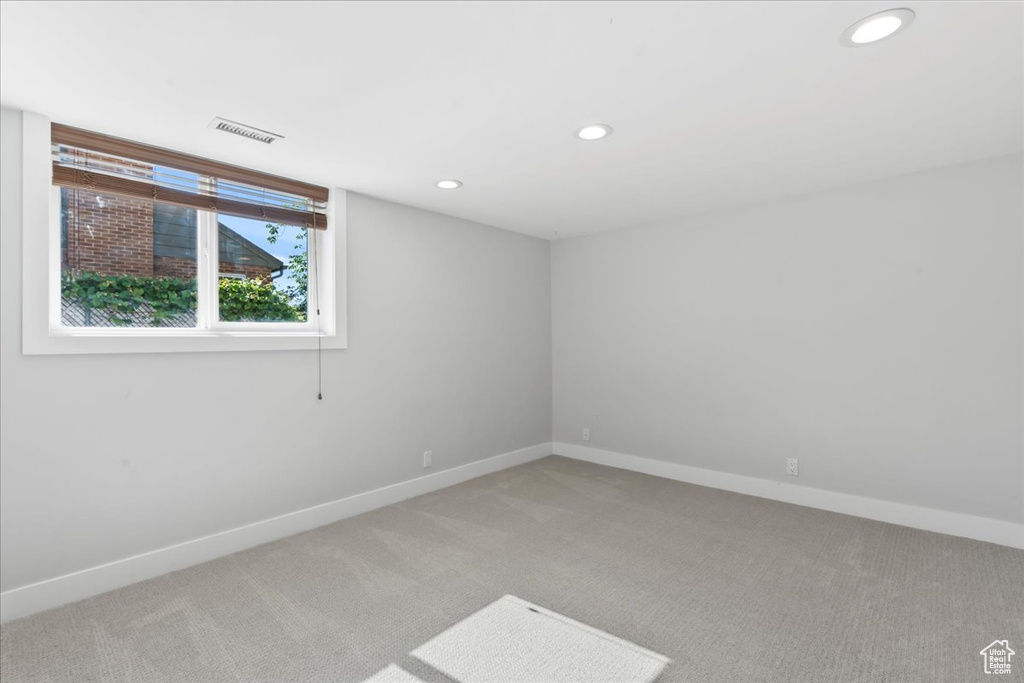 Empty room featuring light colored carpet, baseboards, and recessed lighting