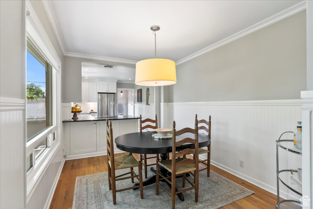 Dining room featuring wainscoting, wood finished floors, and crown molding