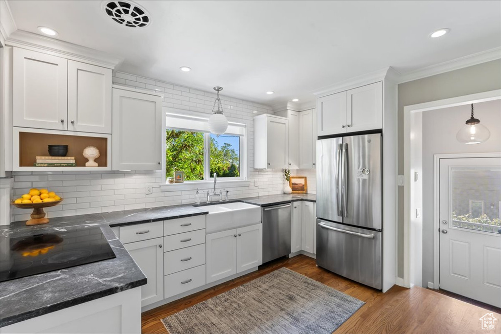 Kitchen featuring appliances with stainless steel finishes, white cabinets, a sink, tasteful backsplash, and ornamental molding