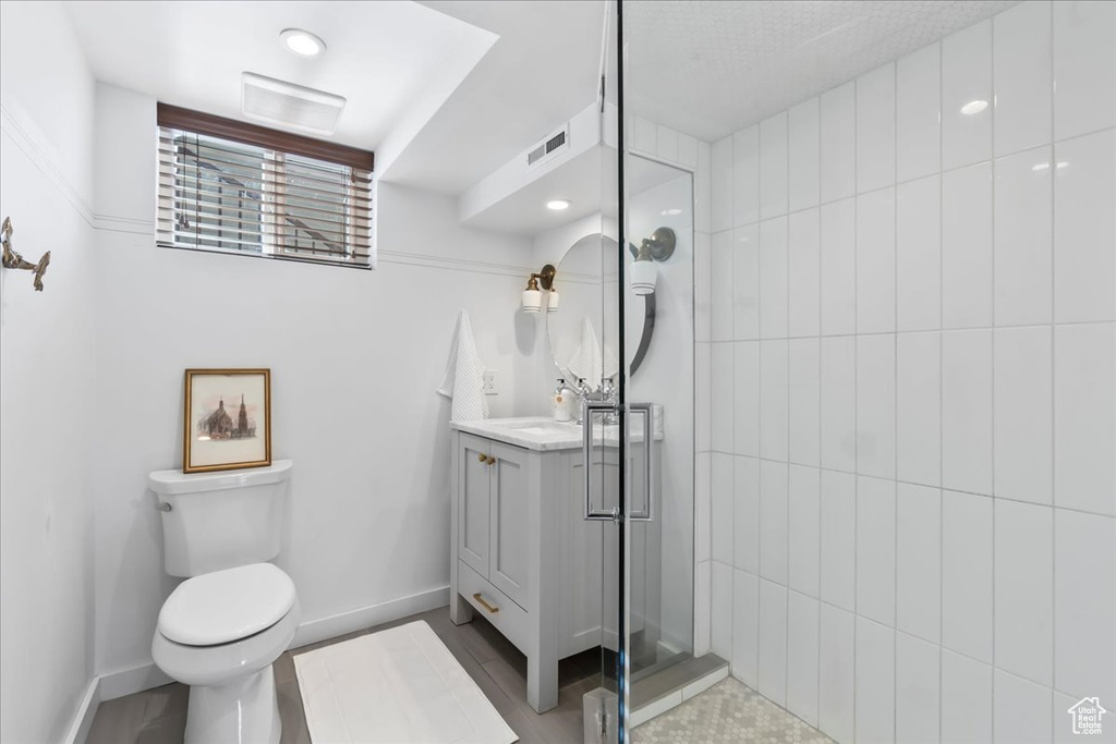 Bathroom featuring vanity, toilet, tiled shower, and baseboards