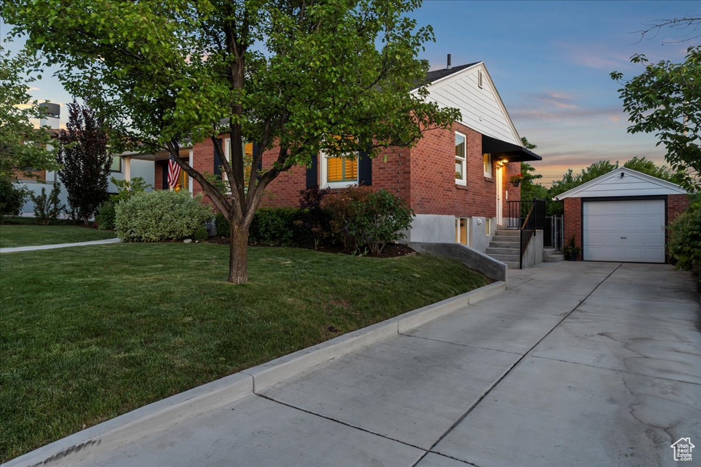 Obstructed view of property with brick siding, an outdoor structure, driveway, a front lawn, and a garage