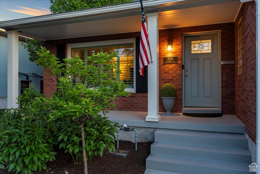 View of exterior entry with brick siding and a porch