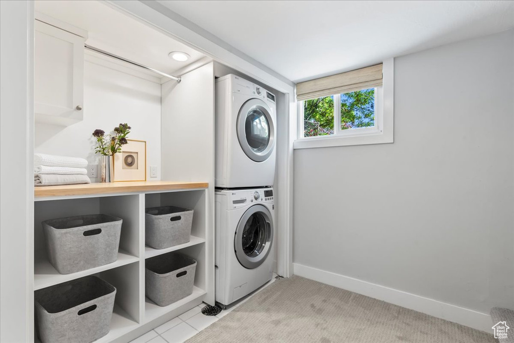 Laundry area featuring stacked washer and clothes dryer and baseboards