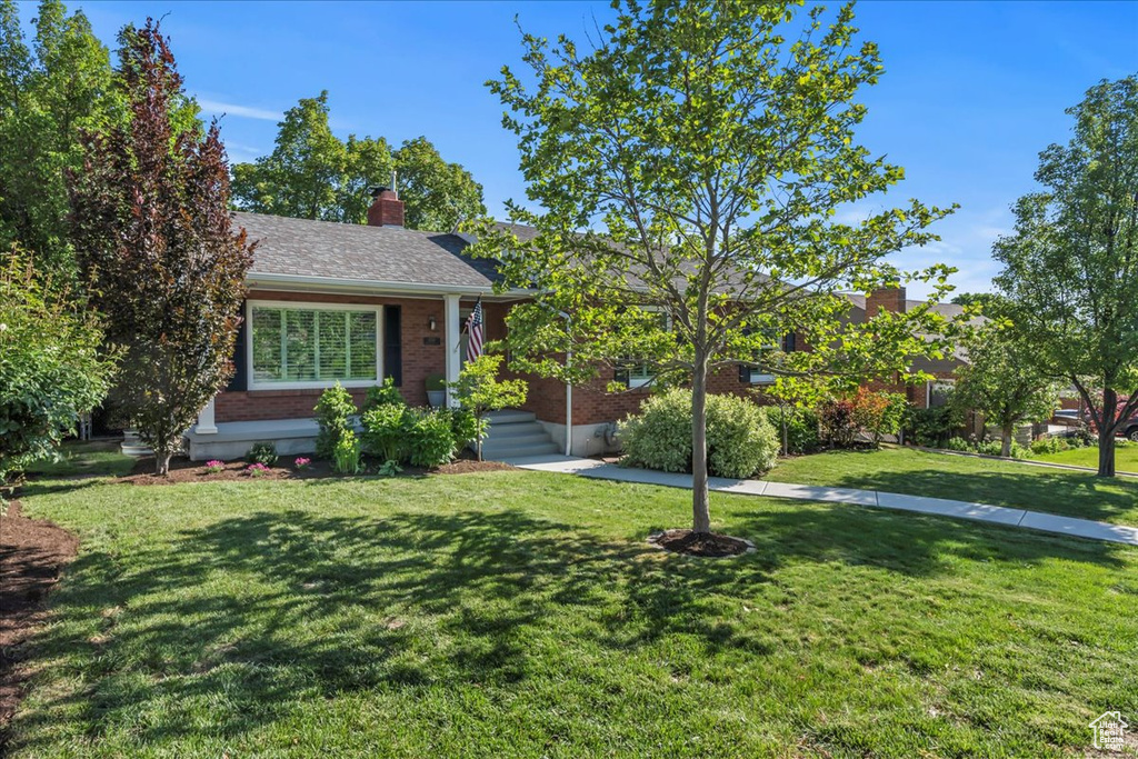 View of front of house featuring a front lawn and brick siding