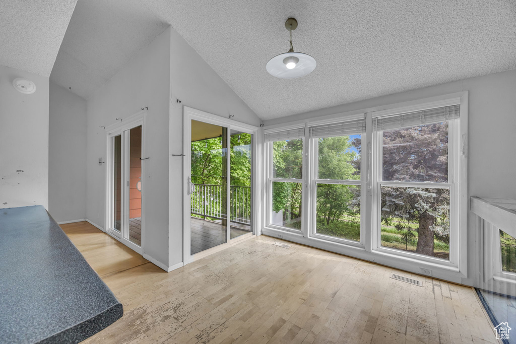 Unfurnished sunroom with lofted ceiling and plenty of natural light