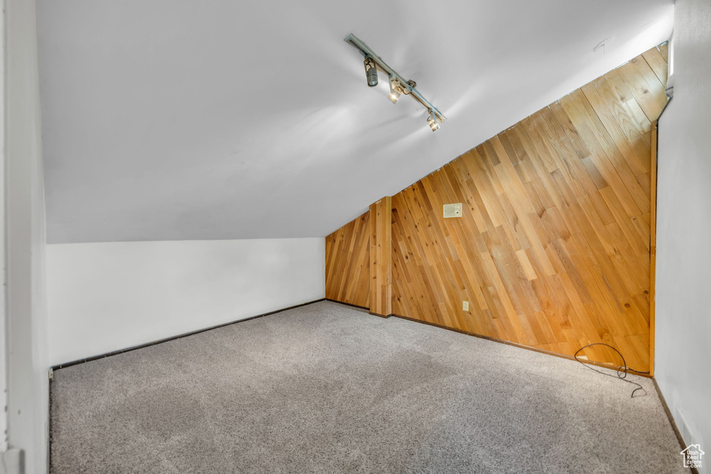 Additional living space with wooden walls, carpet floors, and vaulted ceiling