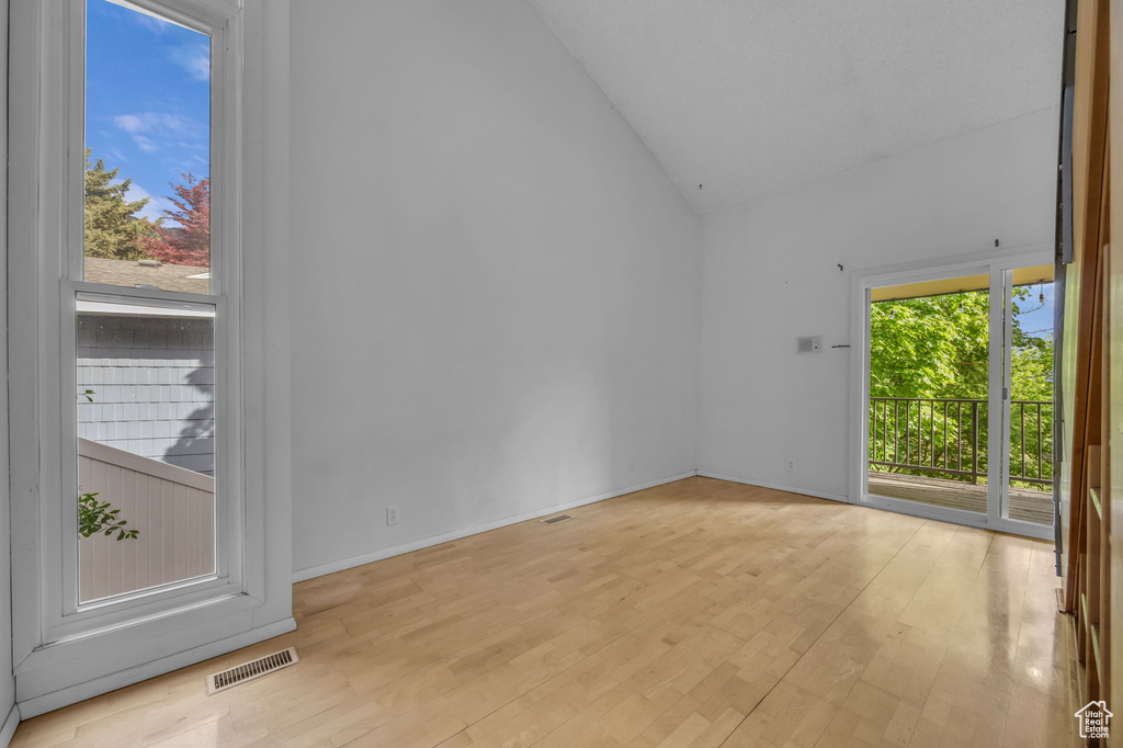 Unfurnished room with wood finished floors and high vaulted ceiling