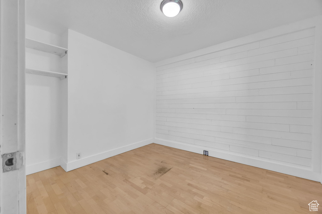 Unfurnished bedroom with baseboards, a textured ceiling, and wood finished floors