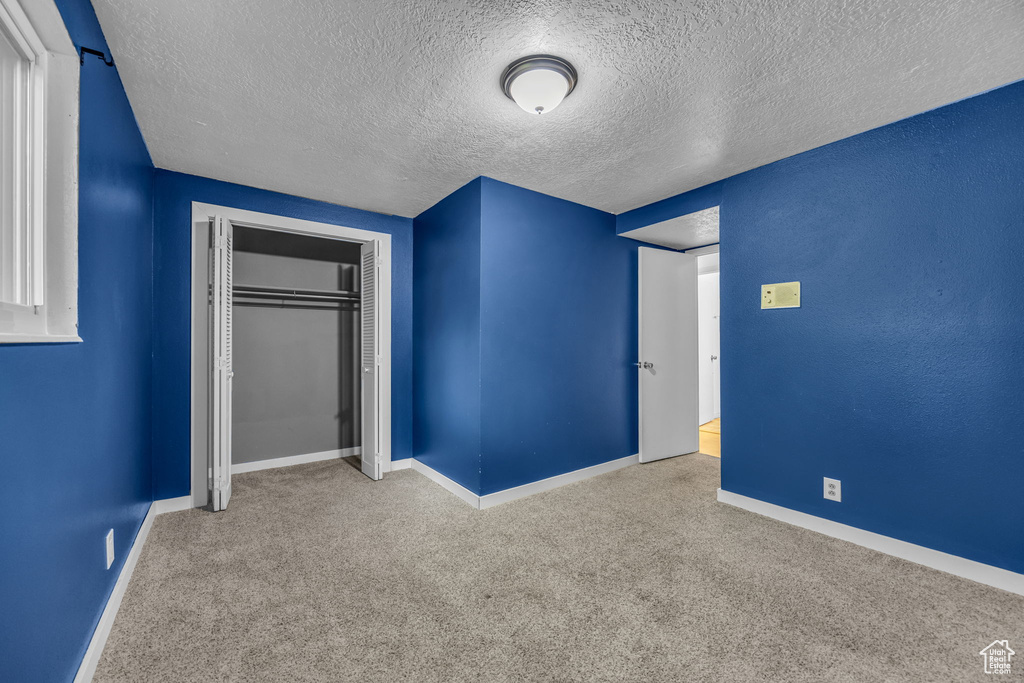 Unfurnished bedroom with carpet flooring, baseboards, a closet, and a textured ceiling