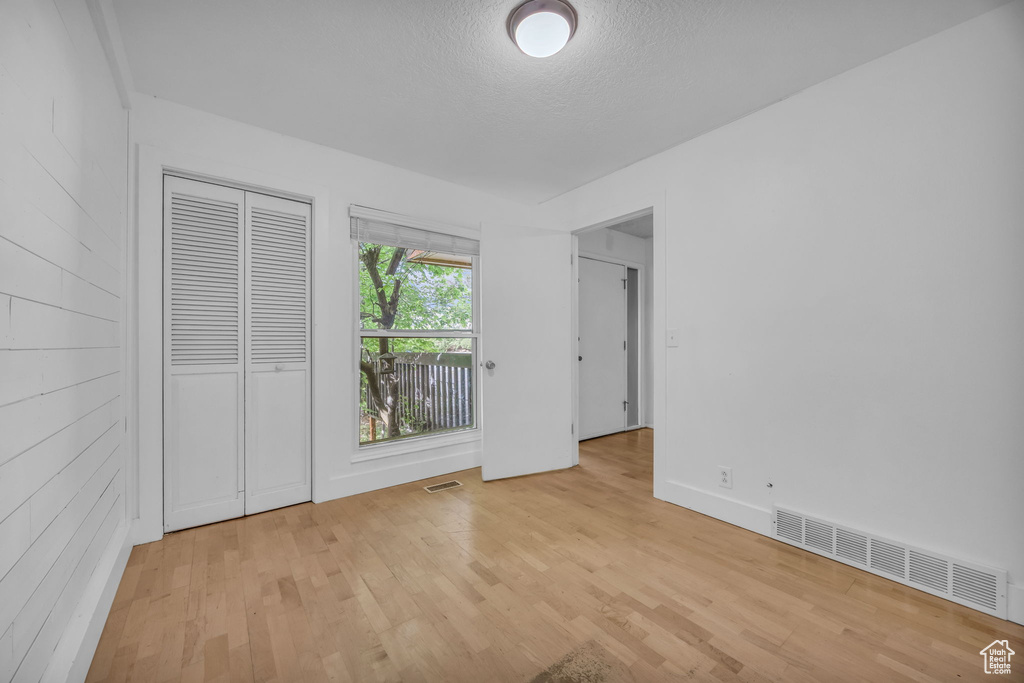 Unfurnished bedroom with light wood finished floors, a textured ceiling, and a closet