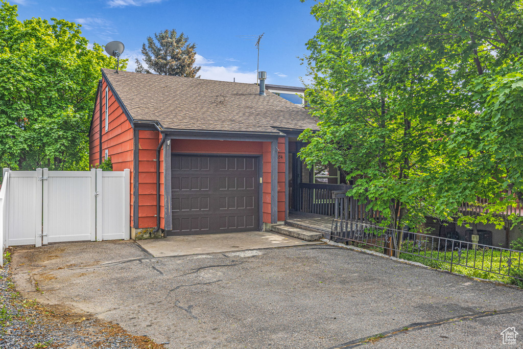 View of front facade with roof with shingles, asphalt driveway, a gate, and a garage