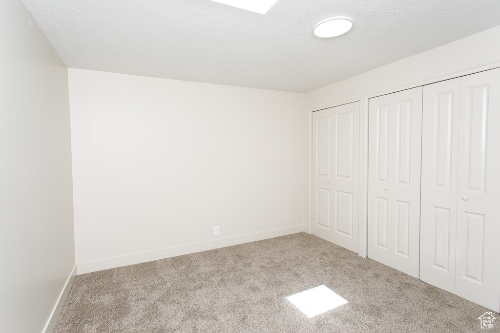 Unfurnished bedroom featuring carpet flooring, baseboards, and two closets