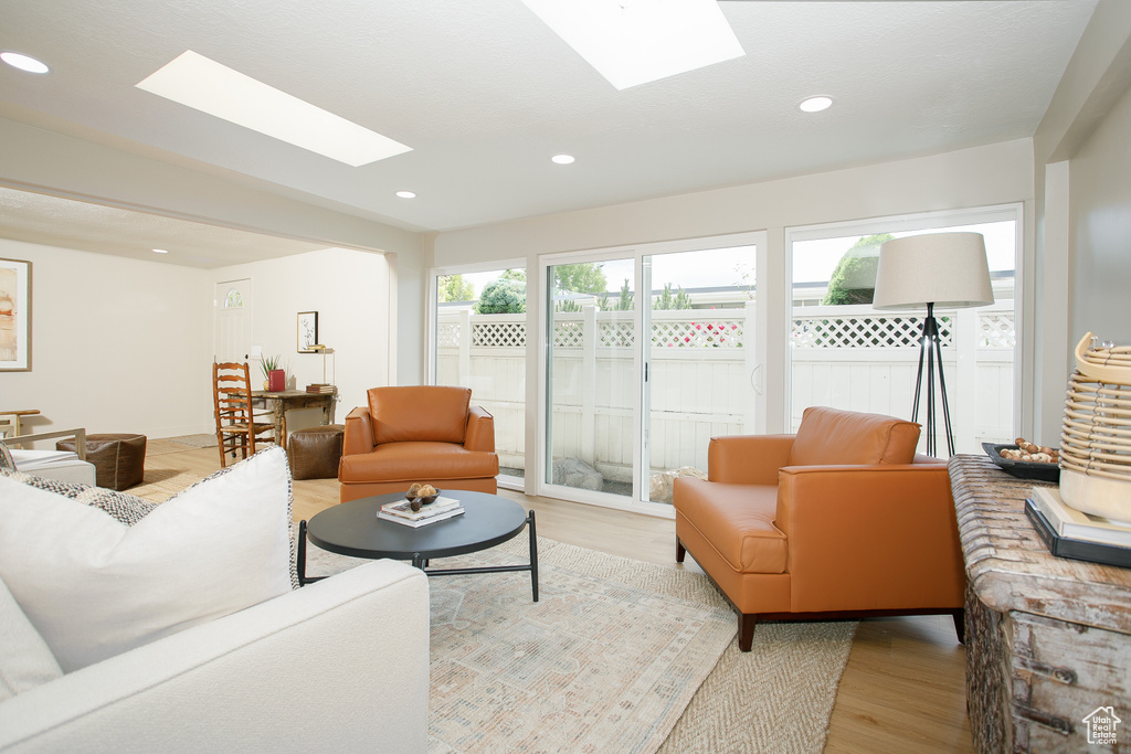 Living area featuring a skylight, light wood-style floors, and recessed lighting