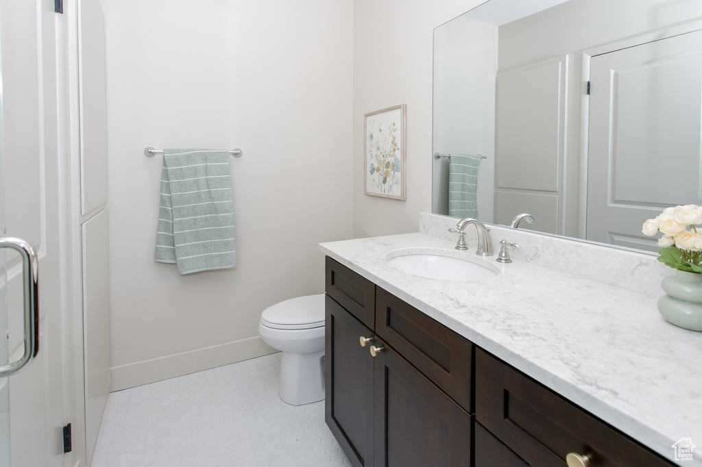 Bathroom with baseboards, vanity, toilet, and tile patterned flooring