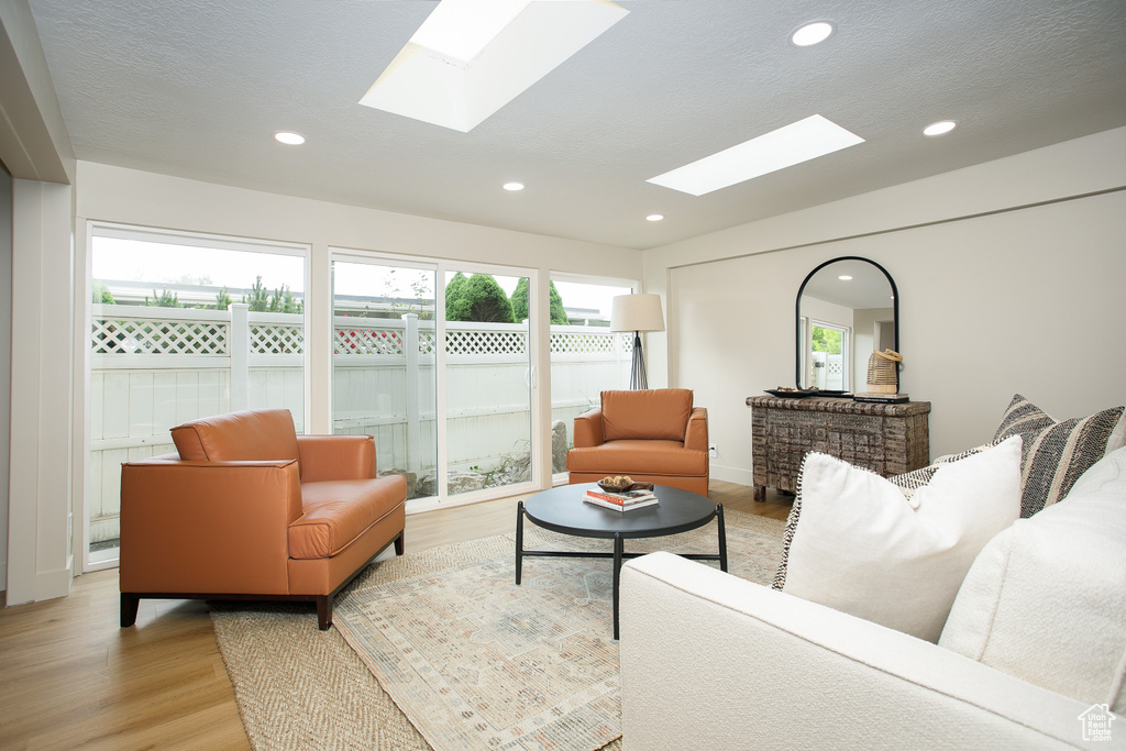 Living room with a skylight, light wood finished floors, and recessed lighting