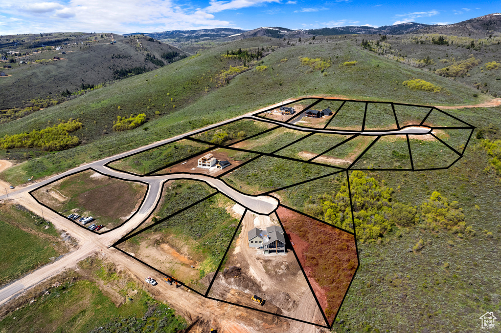 Aerial view of property and surrounding area with property parcel outlined and a mountainous background