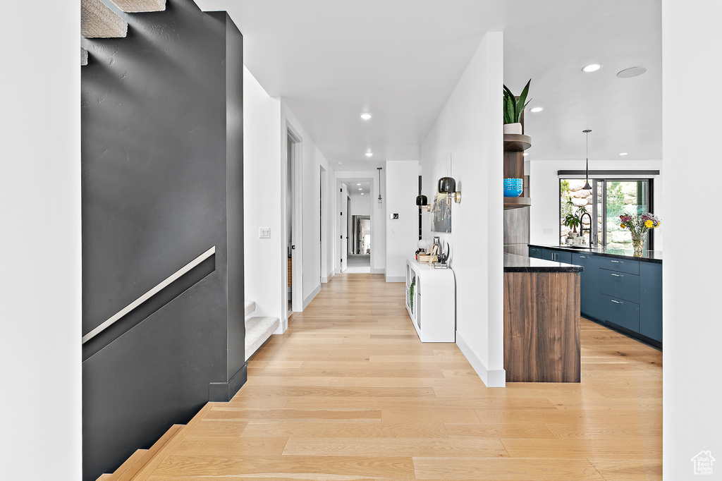 Corridor featuring light wood-style floors, recessed lighting, a sink, and baseboards