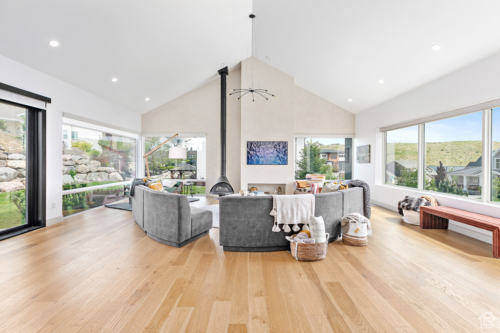 Living room featuring high vaulted ceiling, light wood finished floors, recessed lighting, and a wood stove