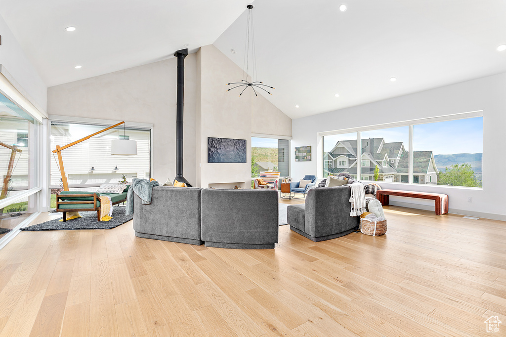 Living room with wood finished floors, high vaulted ceiling, a wood stove, and recessed lighting