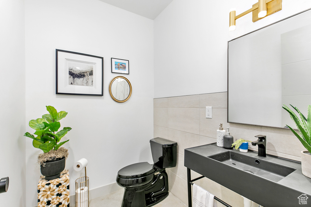 Bathroom with a sink, tile walls, and tasteful backsplash