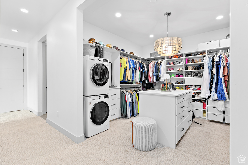 Spacious closet with stacked washer and clothes dryer and light carpet
