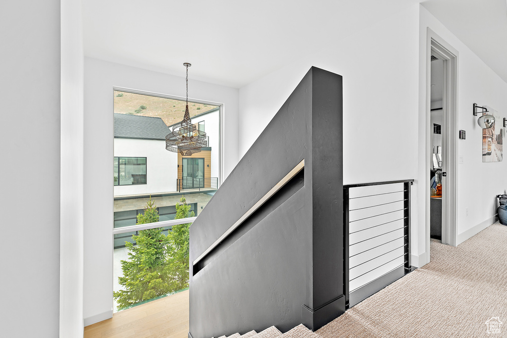 Staircase featuring a chandelier, baseboards, and carpet flooring
