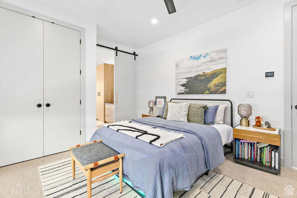 Bedroom with light carpet, a closet, a barn door, and recessed lighting