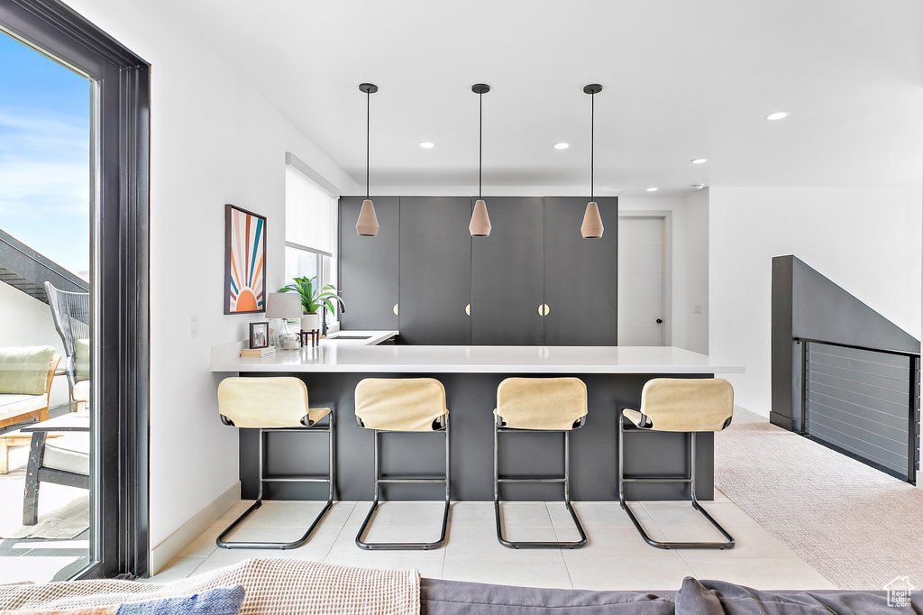 Kitchen featuring a breakfast bar area, light countertops, a sink, a peninsula, and recessed lighting