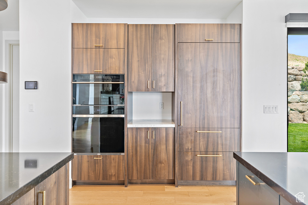 Kitchen with modern cabinets, light wood finished floors, and brown cabinetry