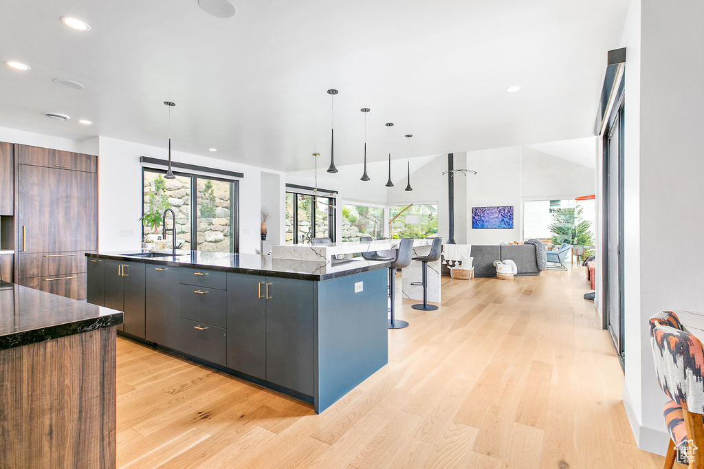 Kitchen with a sink, modern cabinets, light wood-style floors, recessed lighting, and a large island with sink