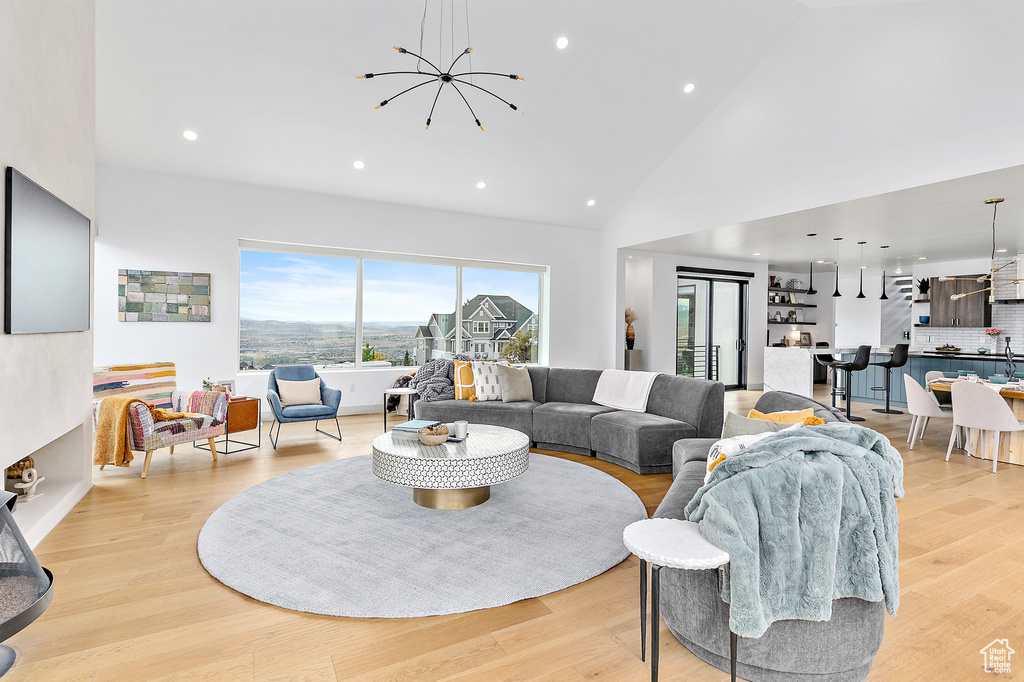Living area featuring a chandelier, recessed lighting, high vaulted ceiling, and light wood-style flooring