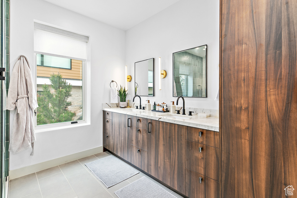 Full bath featuring baseboards, double vanity, and tile patterned floors