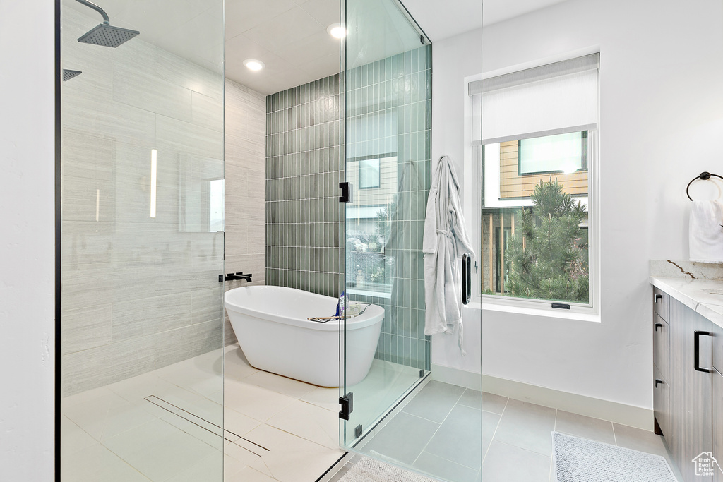Full bathroom featuring walk in shower, tile patterned flooring, a freestanding bath, vanity, and recessed lighting