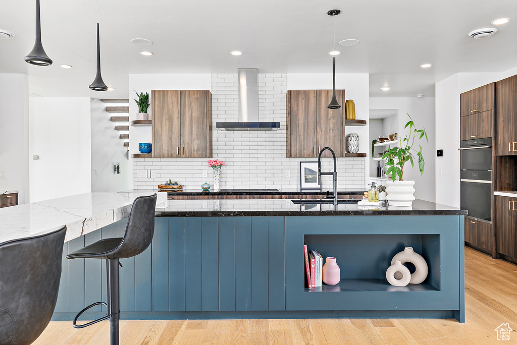Kitchen with open shelves, wall chimney exhaust hood, modern cabinets, a sink, and decorative backsplash