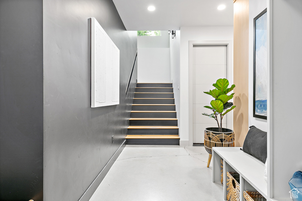 Stairs featuring finished concrete floors and recessed lighting