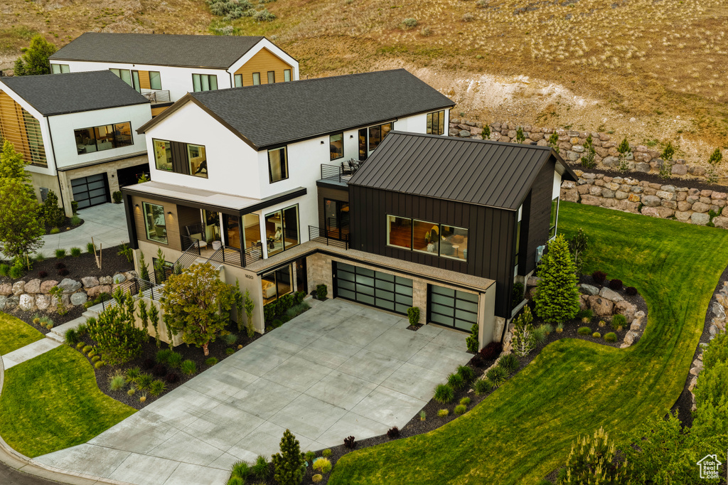 View of front facade with a garage, a balcony, driveway, a front lawn, and stucco siding