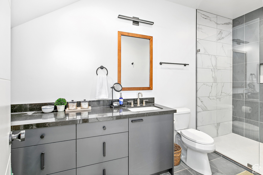 Bathroom with toilet, double vanity, tiled shower, and tile patterned floors