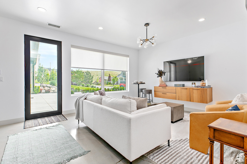 Living room with recessed lighting, a chandelier, and finished concrete flooring