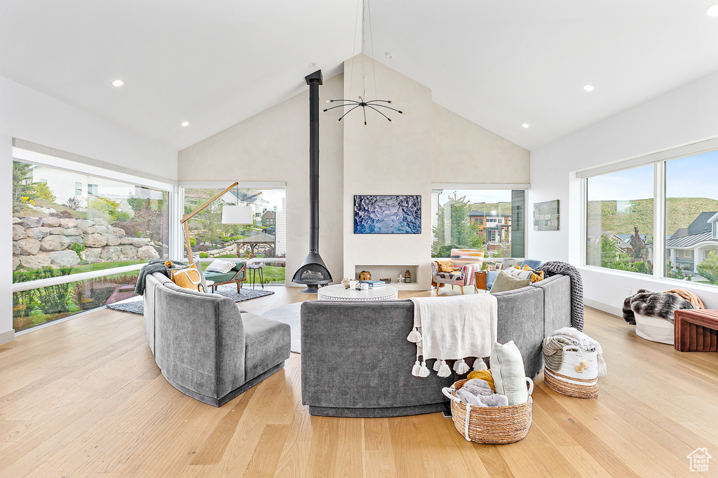 Living room featuring high vaulted ceiling, wood finished floors, a wood stove, and recessed lighting