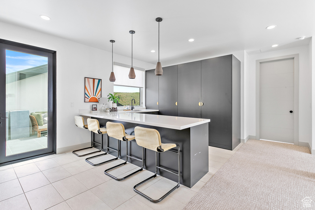 Kitchen featuring a kitchen breakfast bar, light countertops, a peninsula, recessed lighting, and hanging light fixtures