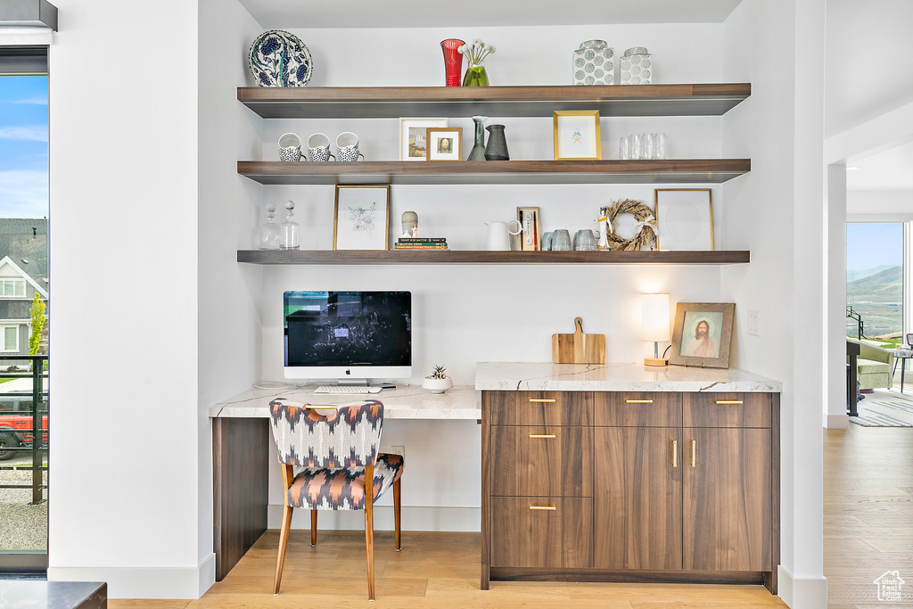Bar featuring built in study area, light wood finished floors, and baseboards