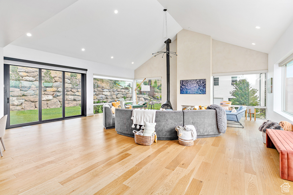 Living area featuring high vaulted ceiling, recessed lighting, healthy amount of natural light, and wood finished floors