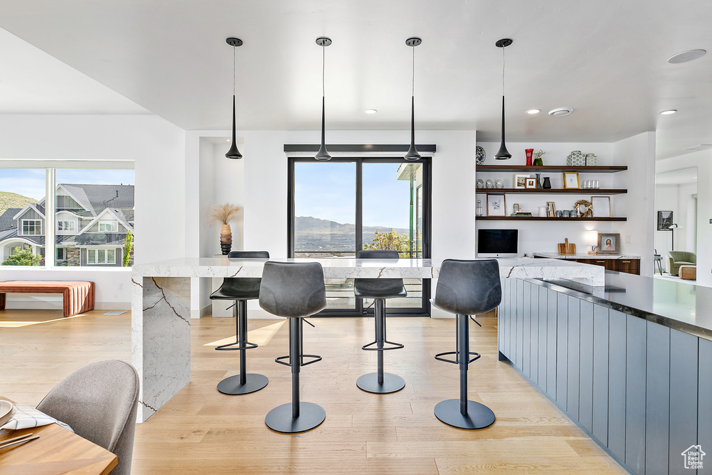 Kitchen featuring light wood-style flooring, open shelves, pendant lighting, dark stone counters, and recessed lighting