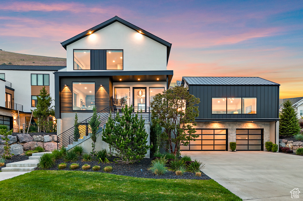 Contemporary home with stairway, concrete driveway, an attached garage, board and batten siding, and a standing seam roof