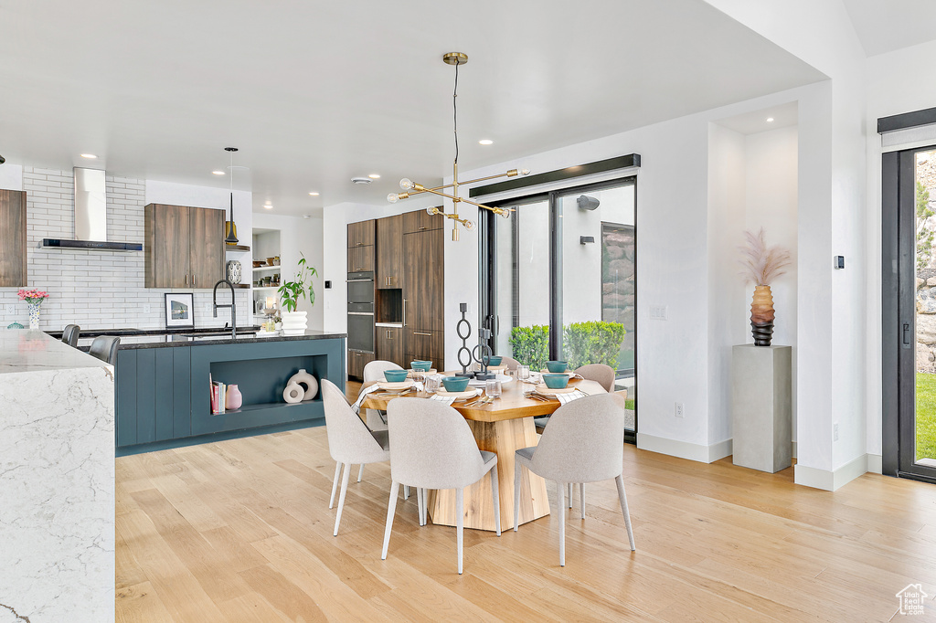 Dining space with light wood finished floors, recessed lighting, a chandelier, and baseboards