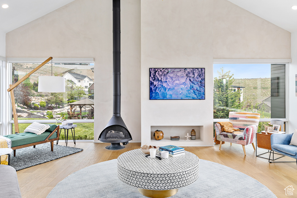 Living room with high vaulted ceiling, a wood stove, wood finished floors, and recessed lighting