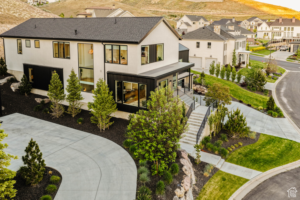 View of front of home with a shingled roof, stairway, a residential view, and stucco siding